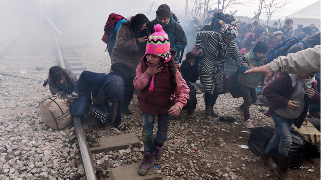 A child coughs as migrants and refugees run away after Macedonian police fired tear gas at hundreds of Iraqi and Syrian migrants who tried to break through the Greek border fence in Idomeni, on February 29, 2016. Greek police said more than 6,000 people were massed at the border, in a buildup triggered by Austria and Balkan states capping the numbers of migrants entering their territory. / AFP / LOUISA GOULIAMAKI